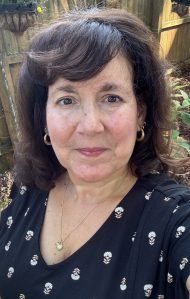 Dark haired woman in a garden wearing a black dress